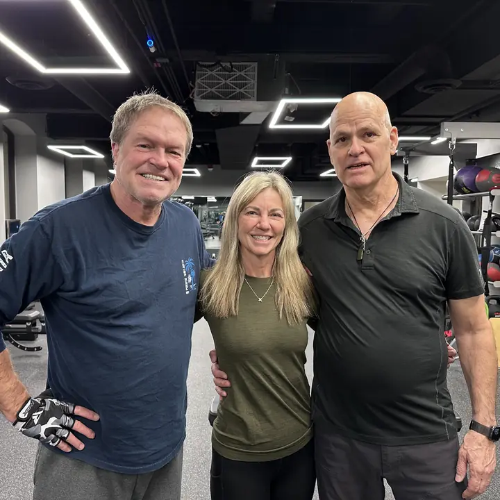Two men and a woman standing together in the gym