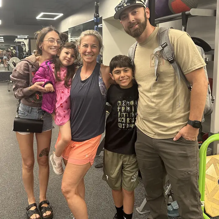 A family of five smiling together in the gym