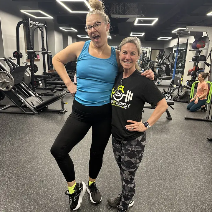 Two women posing playfully on the gym floor